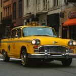 Vintage yellow taxi cab driving through bustling New York City street with iconic buildings.